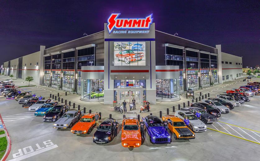 Summit Racing storefront evening with custom vehicle lineup